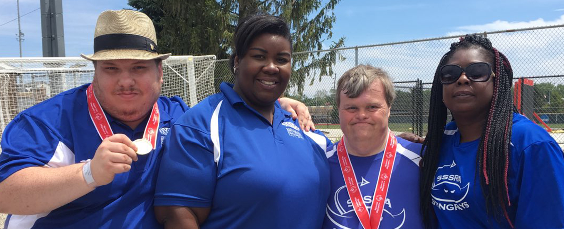 2 Special Olympics athletes and 2 Special Olympics coaches. The athletes are wearing medals.