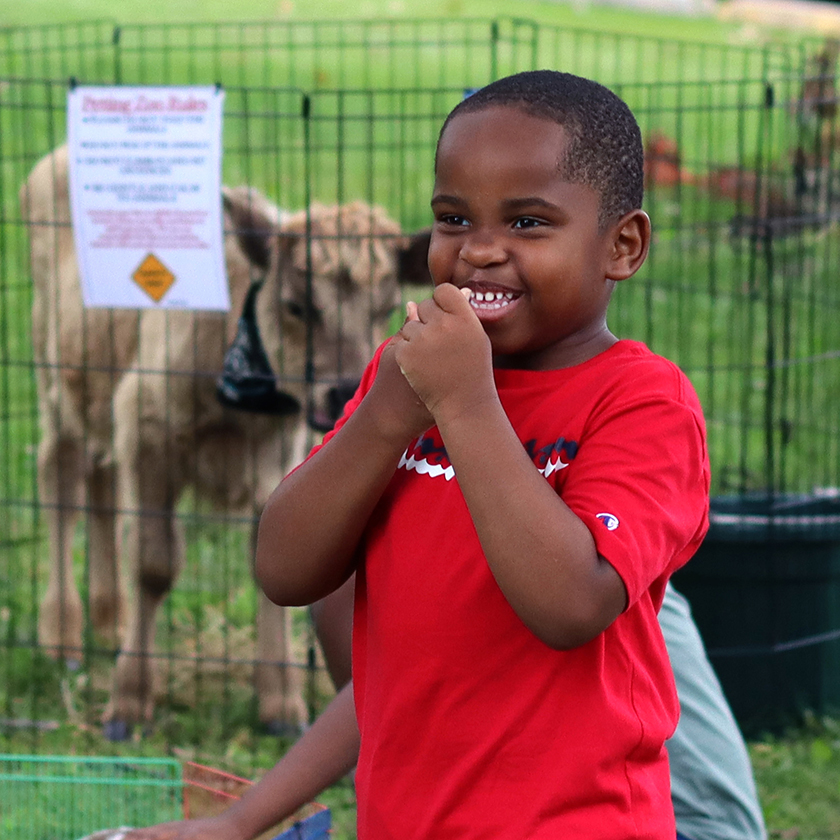 All Camp & Family Day participant smiles at the petting zoo.