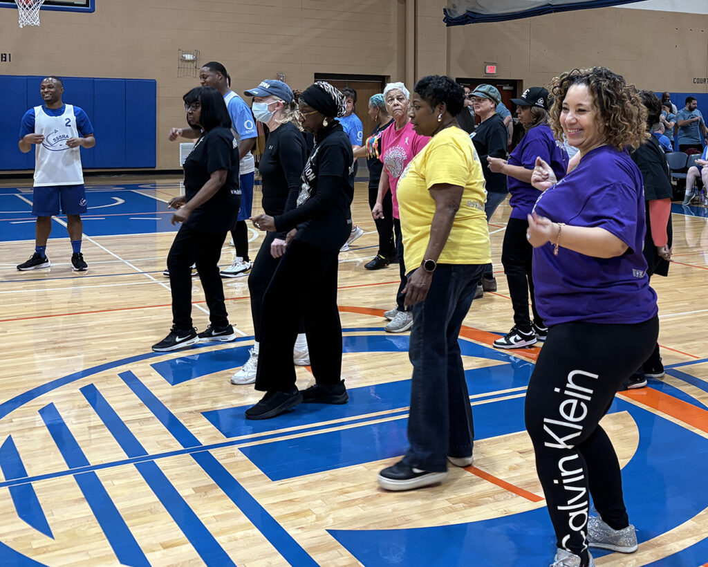 Group of people dancing in a gymnasium.