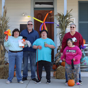 Family posing on a porch, decorated with pumpkins, hay, and corn stalks.