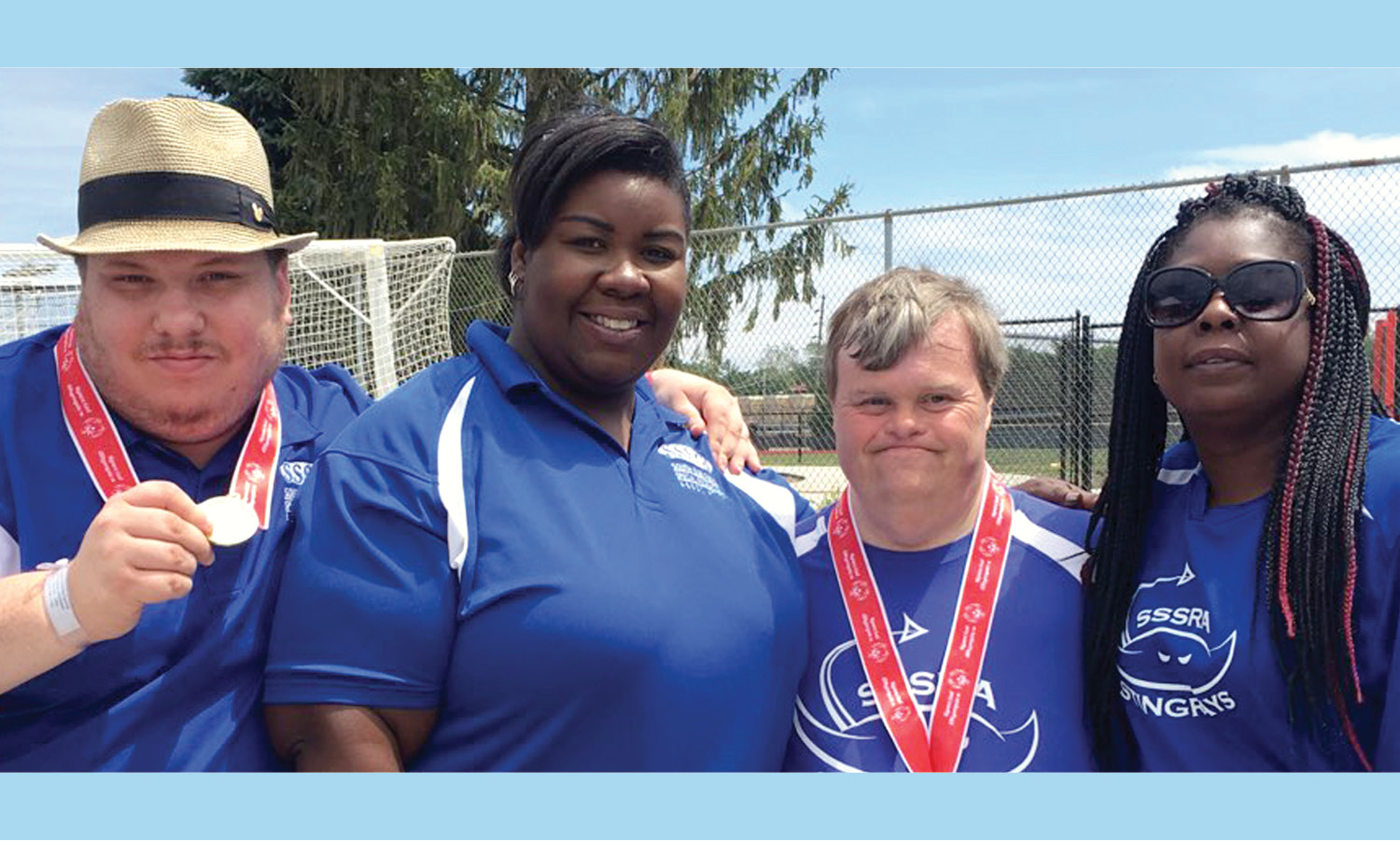 2 Special Olympics athletes and 2 Special Olympics coaches. The athletes are wearing medals.