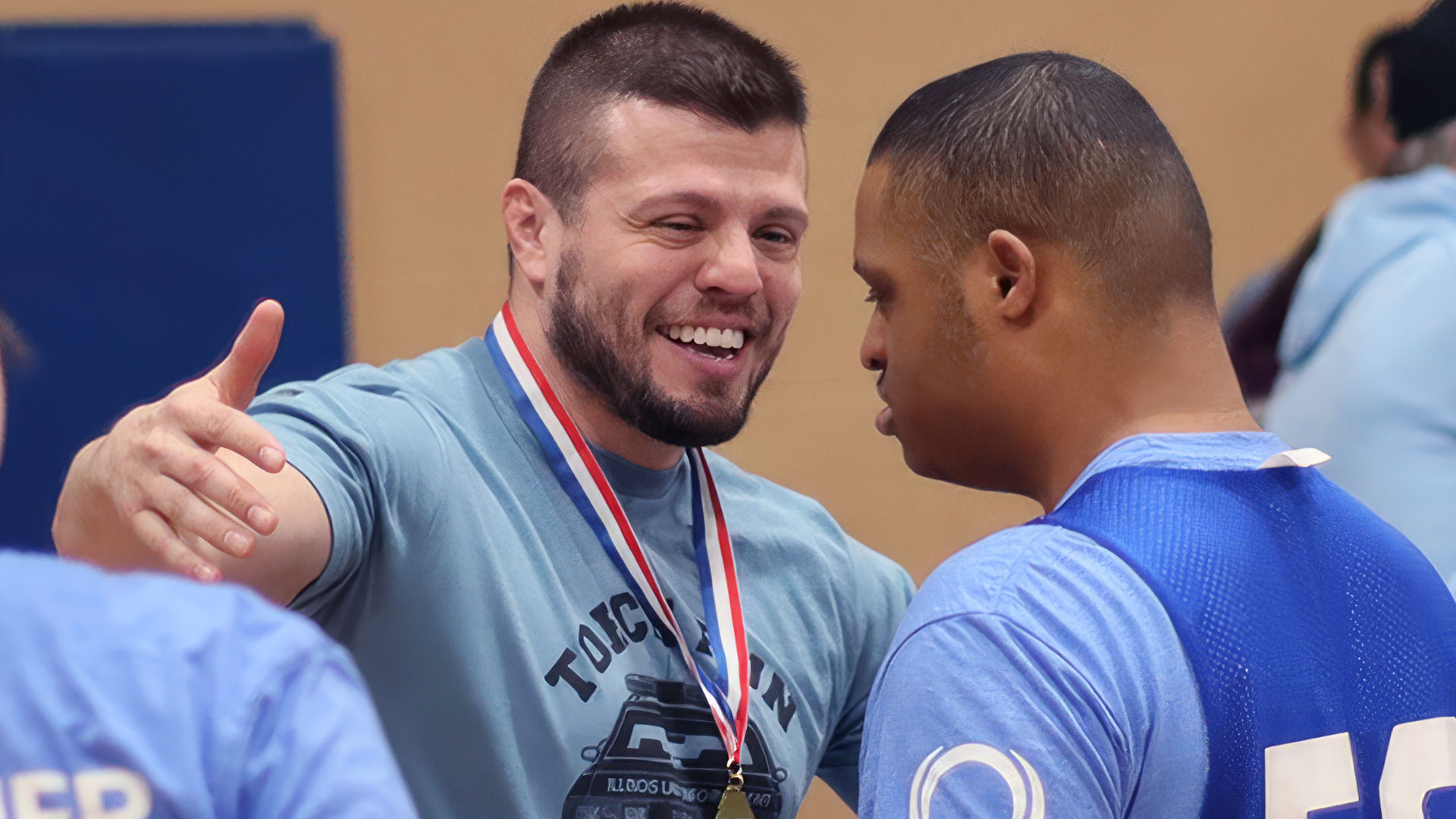 Two people embracing with medals, wearing 'Together we are stronger' shirts.